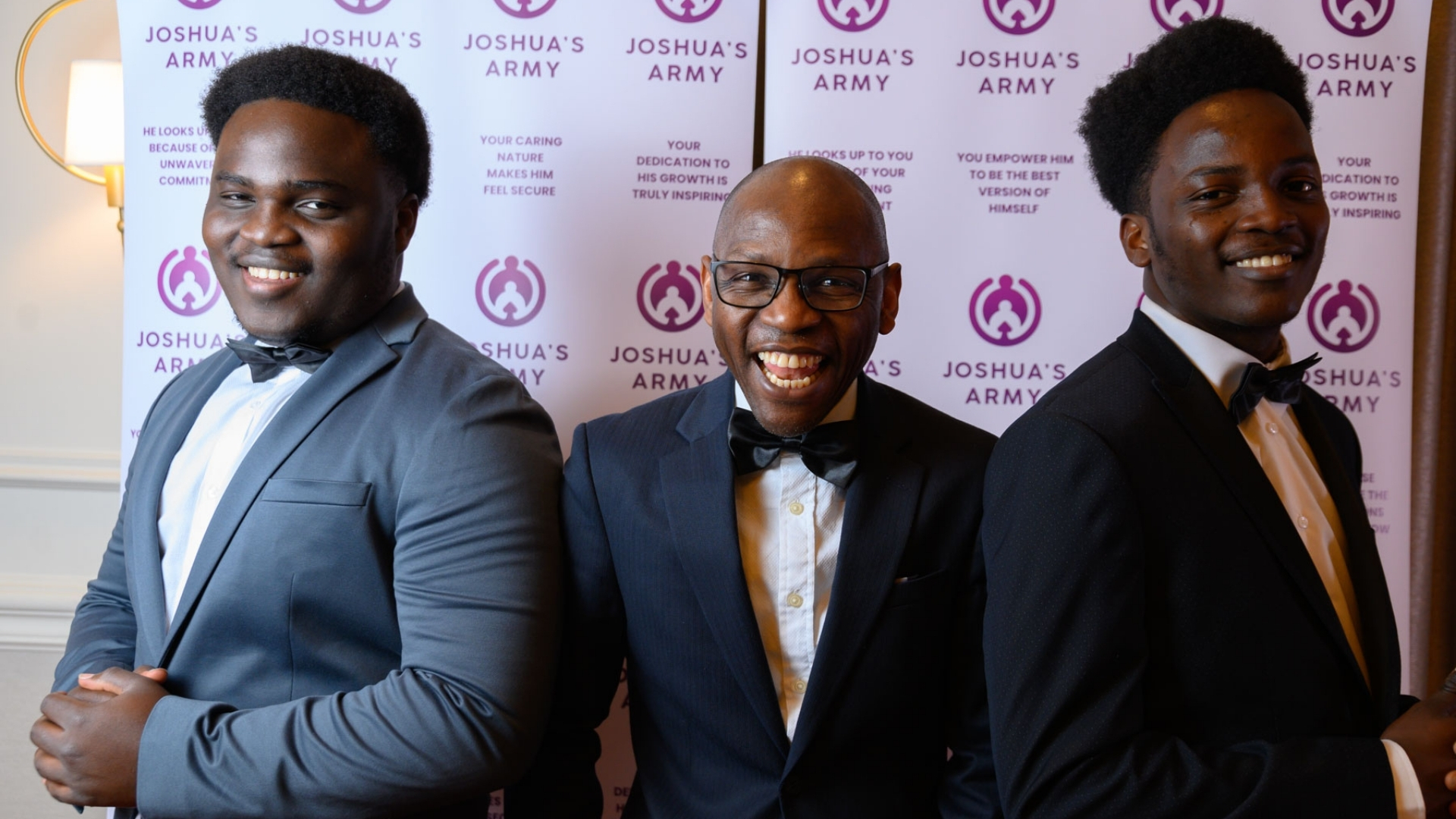 Father laughing joyfully with two sons in formalwear